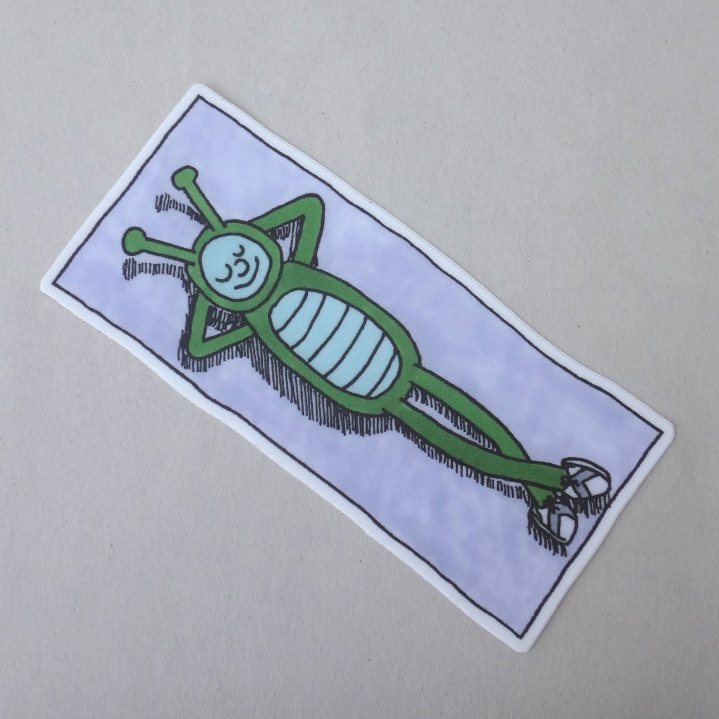 A sticker of Bug Boy laying on a beach towel