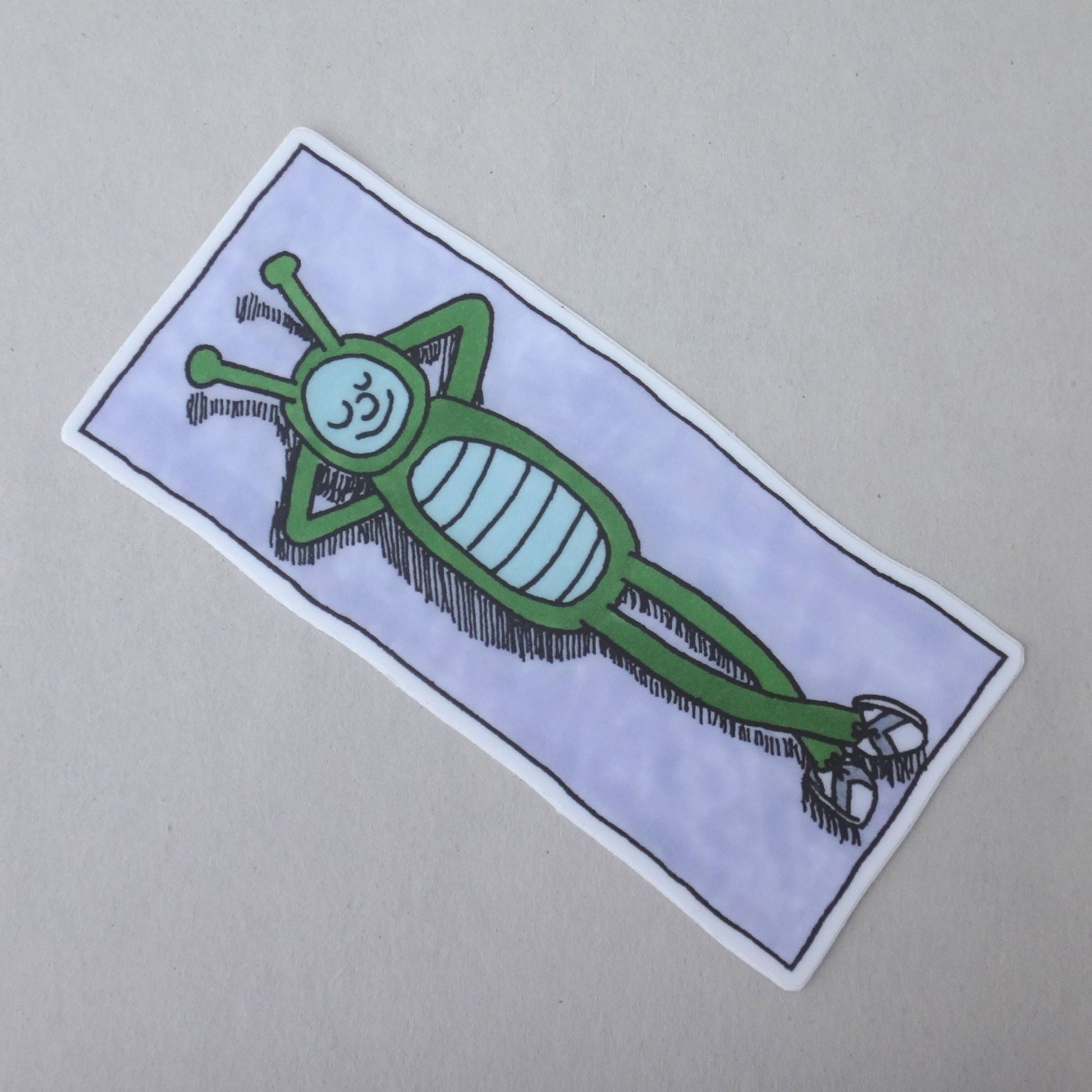 A sticker of Bug Boy laying on a beach towel