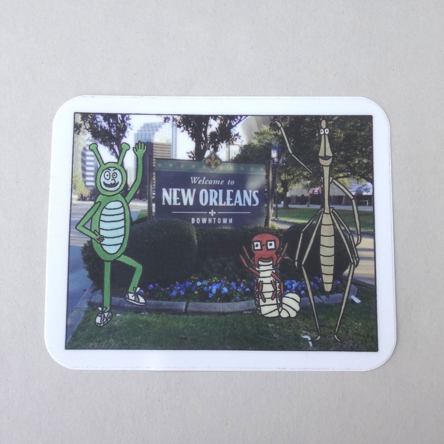 A sticker of Bug Boy, Seymour, and Will standing in front of the New Orleans sign