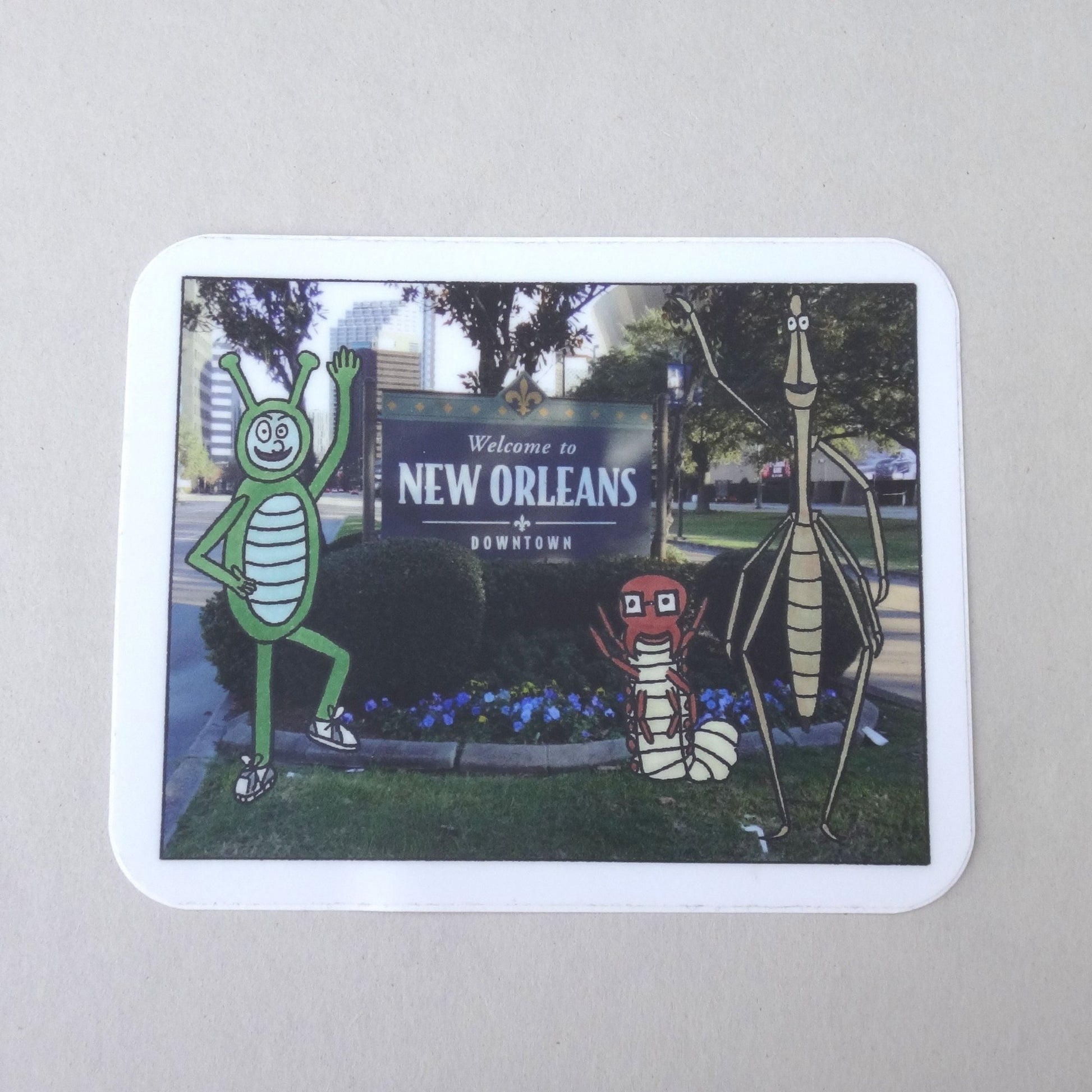 A sticker of Bug Boy, Seymour, and Will standing in front of the New Orleans sign